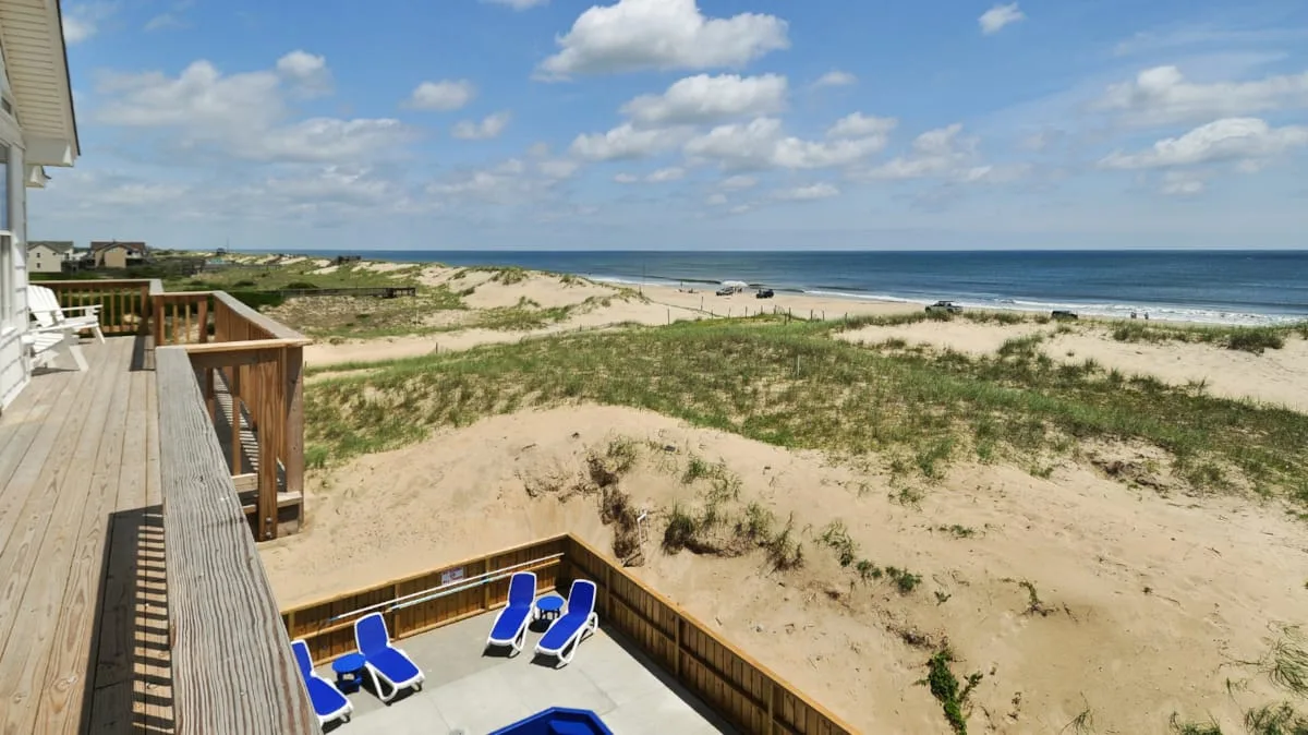 A beachside deck overlooks sandy dunes and the ocean.