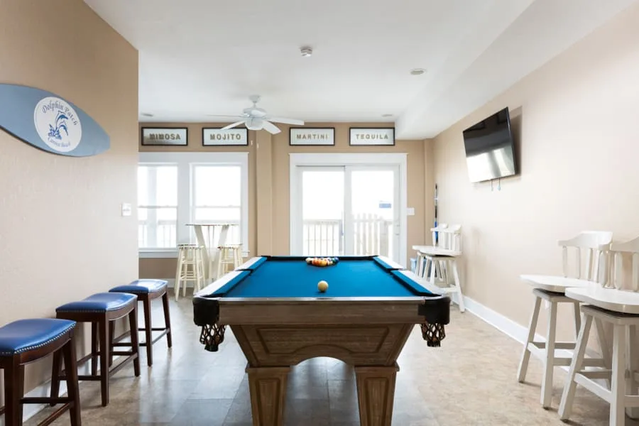 A game room features a pool table and seating along the walls.
