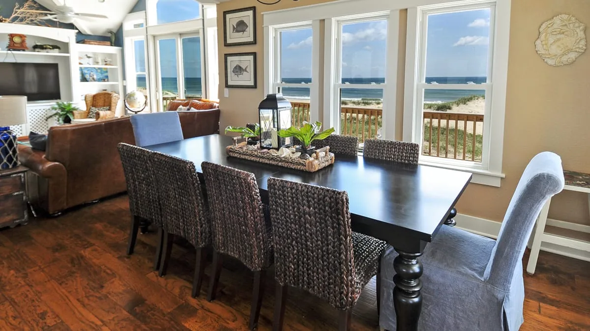 A dining area with a dark table and windows overlooking the ocean.