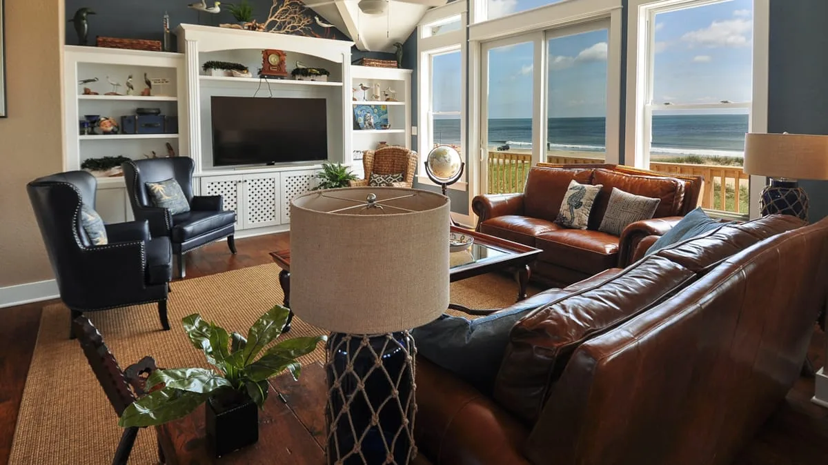 A living room with leather seating and large windows overlooking the ocean.