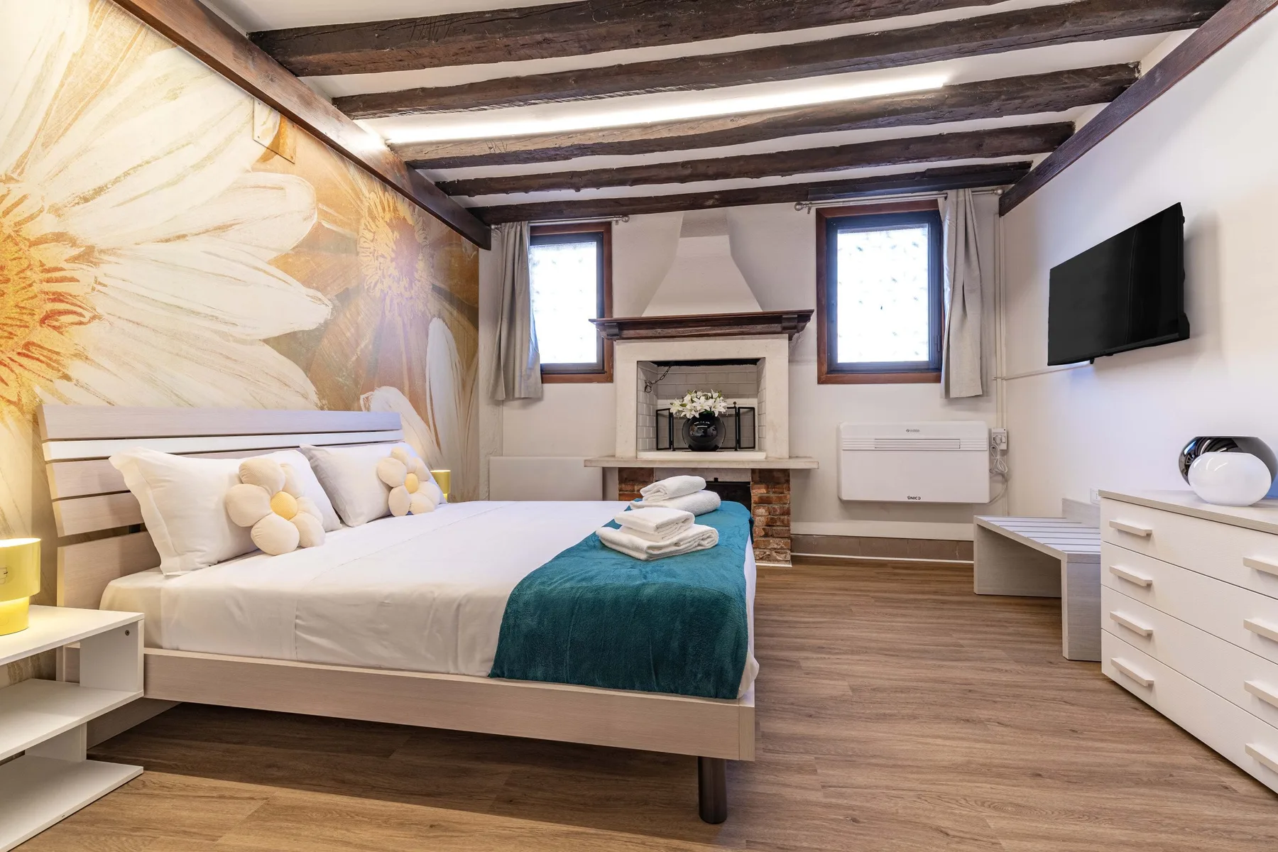 Un dormitorio con una cama, una chimenea y un gran mural floral.