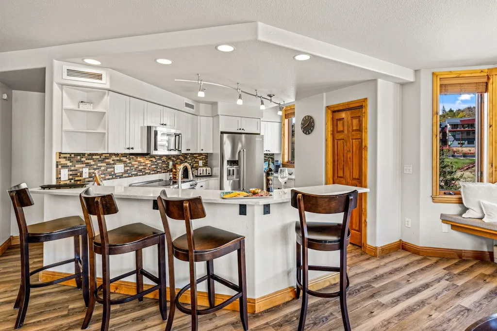 Una cocina abierta con comedor, barra y taburetes de madera.