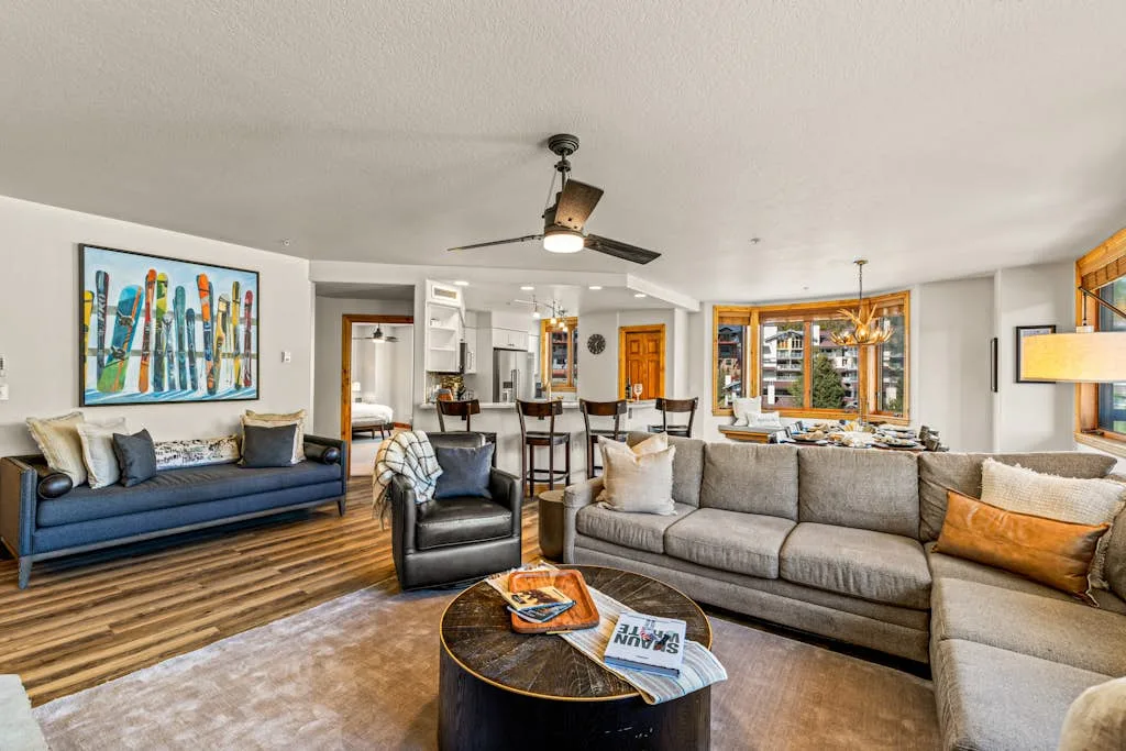A bright living room with seating, a coffee table, and a dining area beyond.