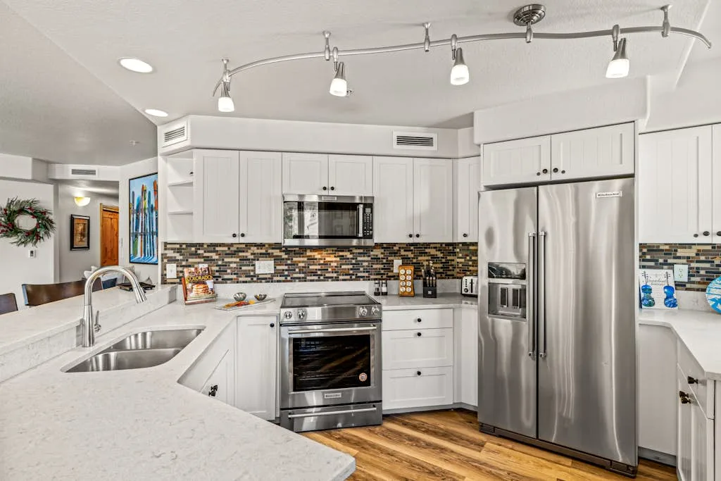 A bright kitchen with white cabinets, stainless steel appliances, and a broad island.