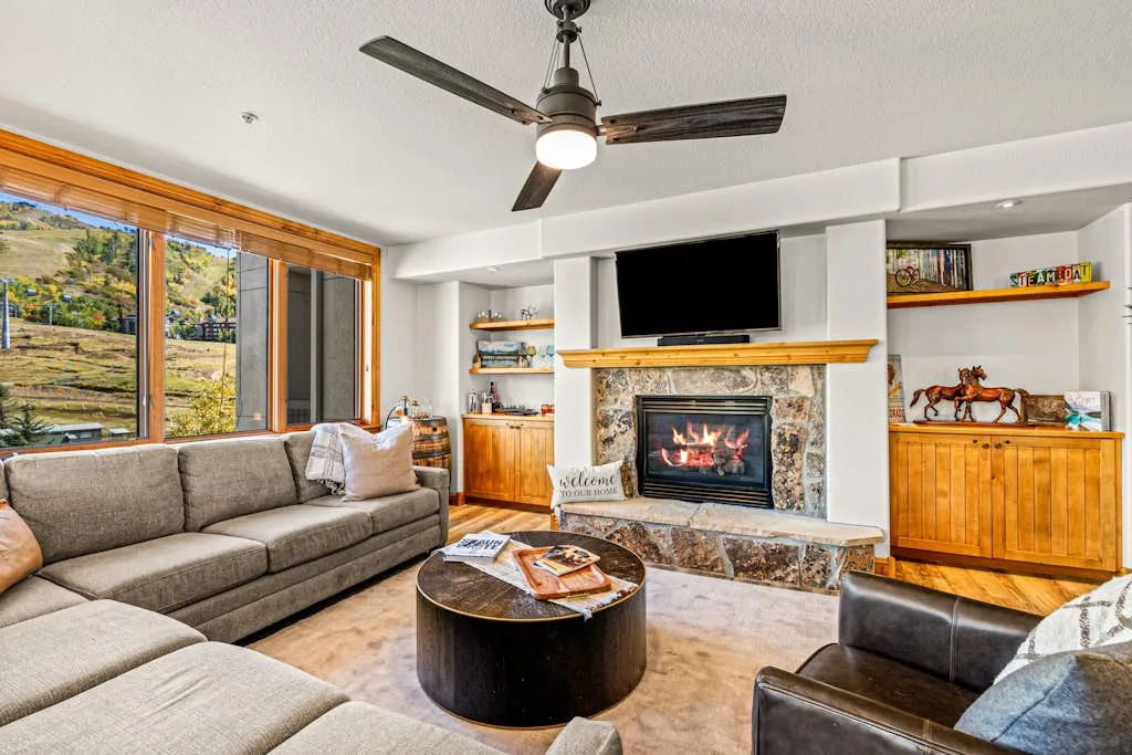 A living room with a fireplace, seating, and a television.