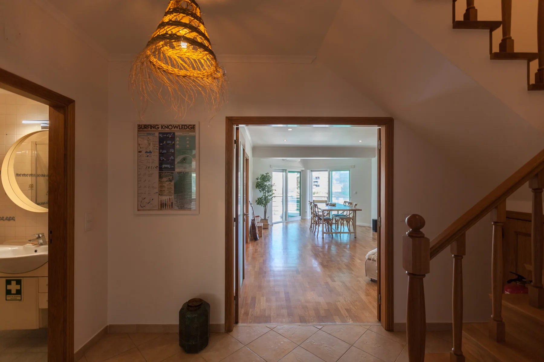 An interior hallway opens toward a bright dining area, with a staircase along the right wall.