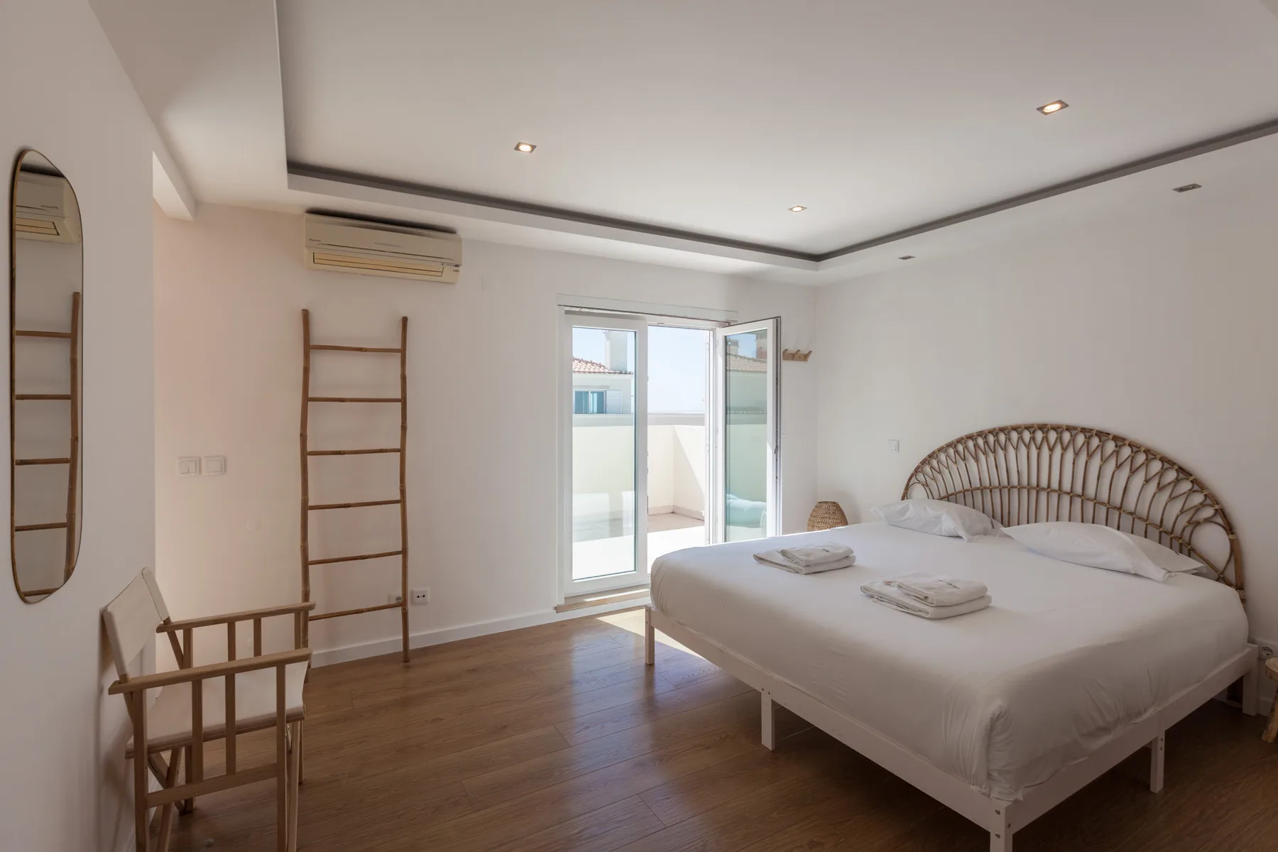 A bright bedroom with a bed and glass doors opening onto a balcony.