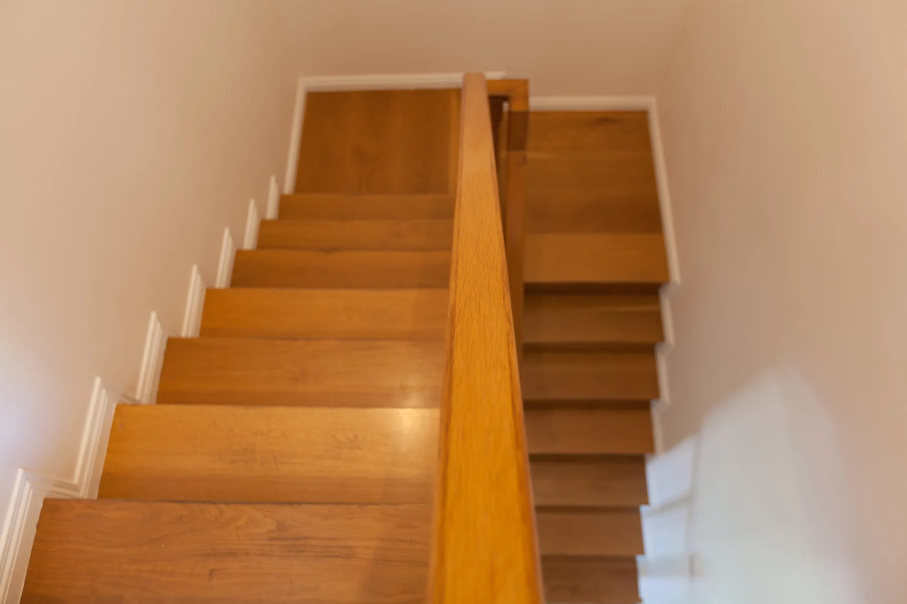 A wooden staircase rises between white walls.
