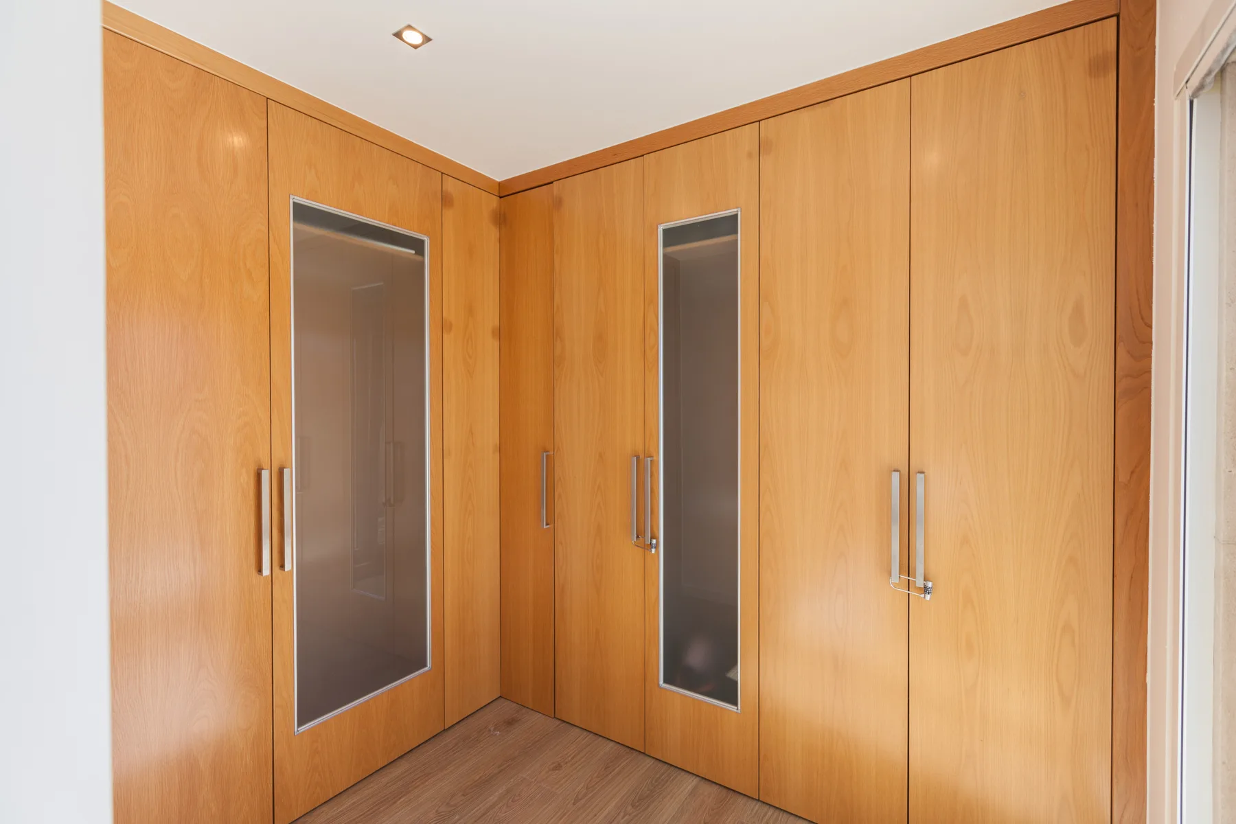 A built-in wooden wardrobe with tall mirrored panels fills the corner of the room.