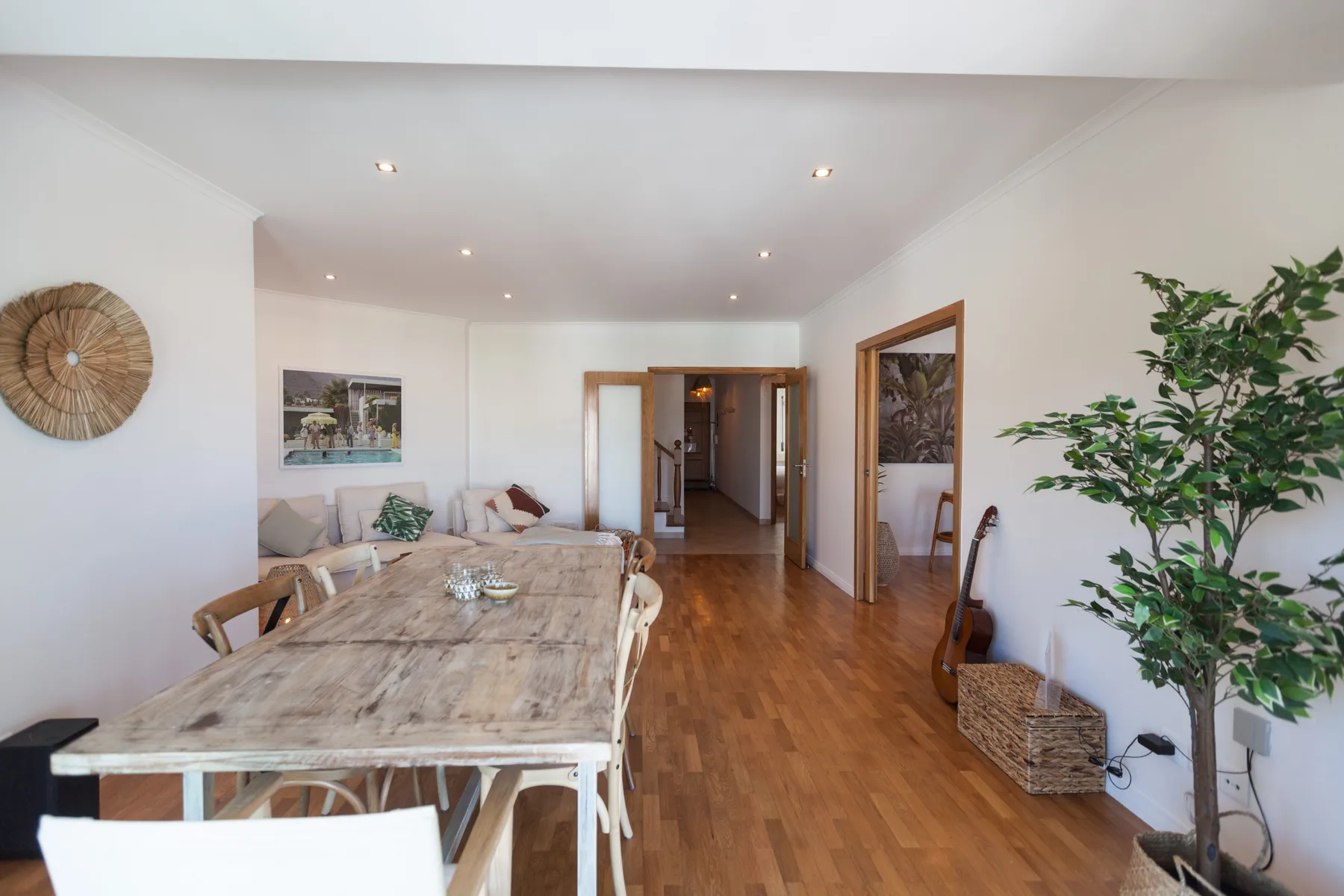 A bright dining area with a long table, seating, and a wooden floor.