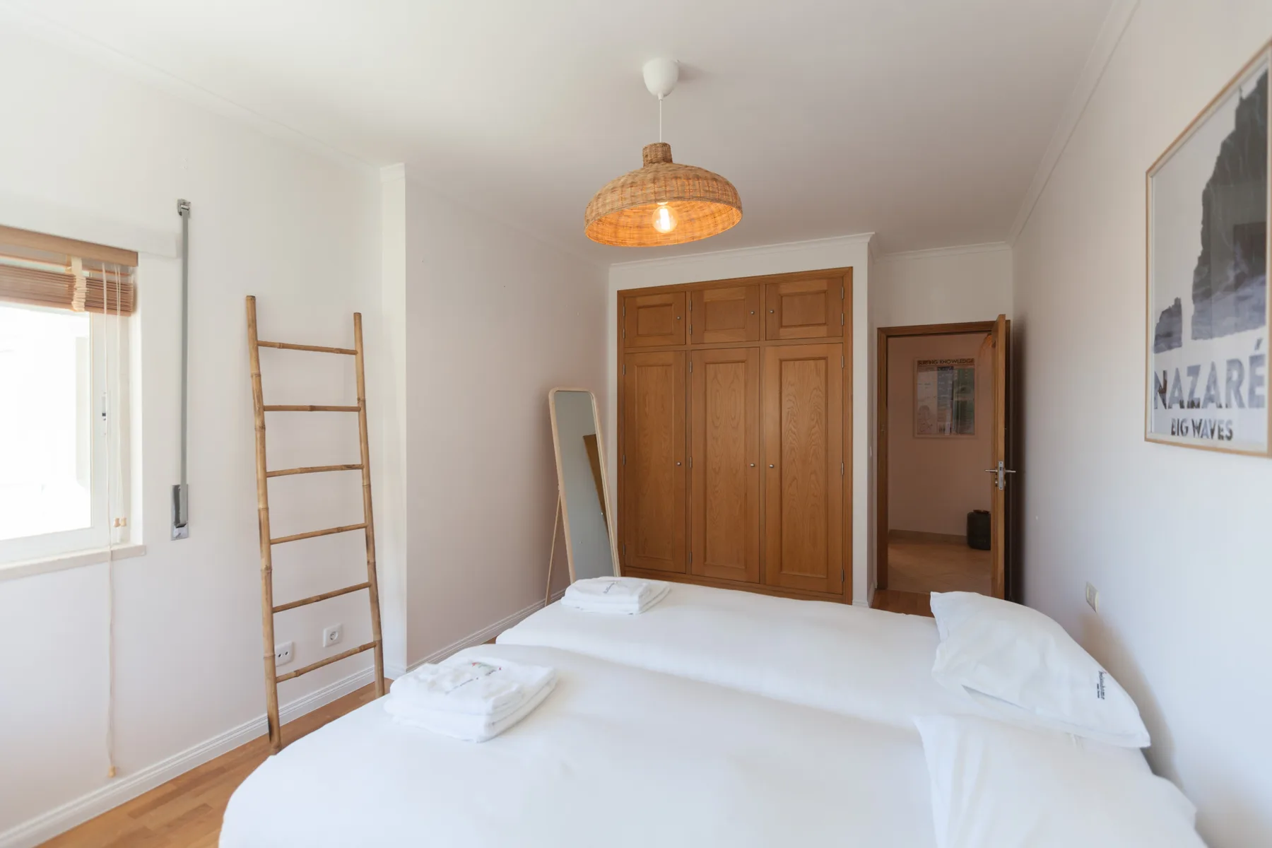 A bright bedroom with a large wooden wardrobe and a bed.