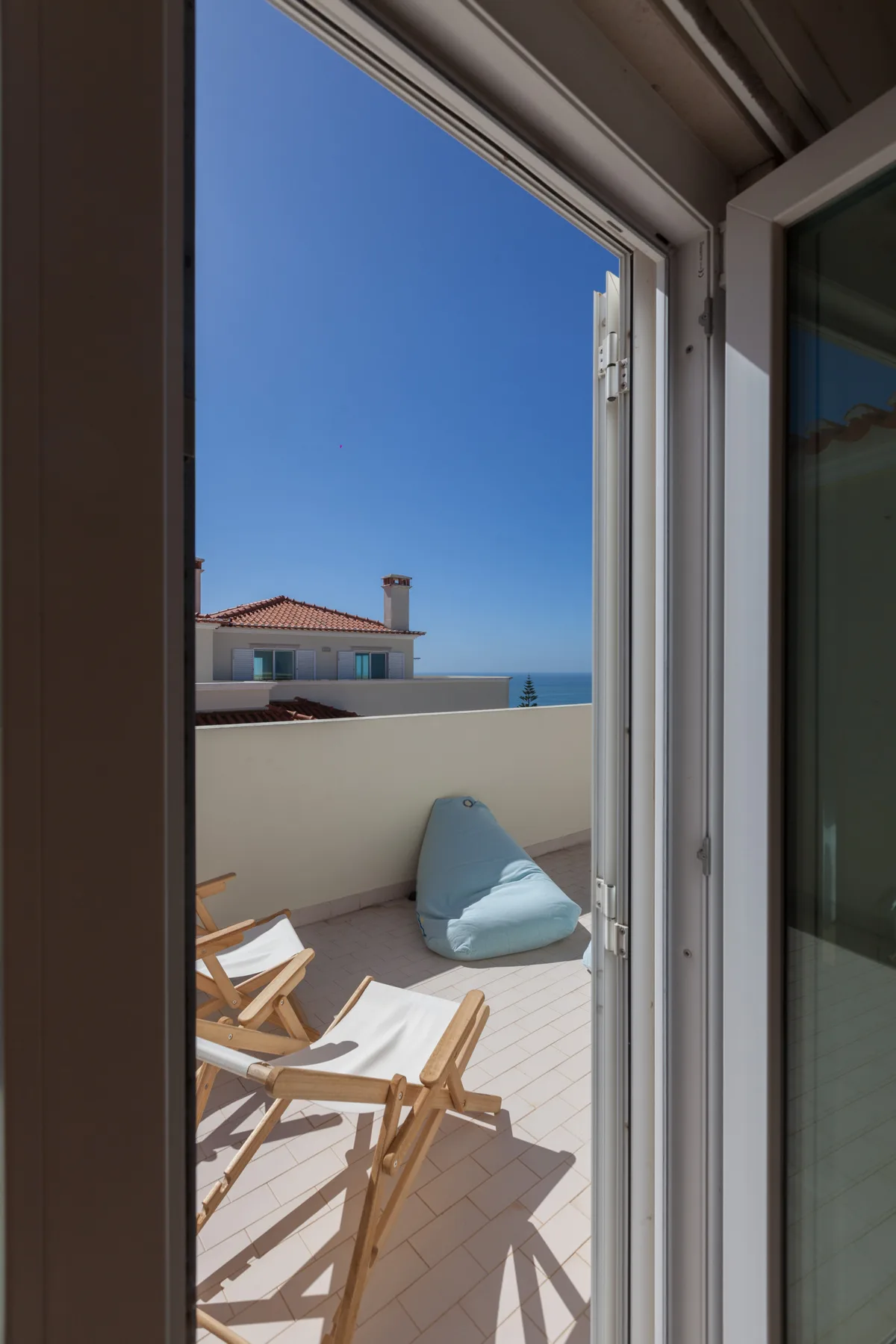 A sunlit terrace with outdoor seating overlooks the sea.