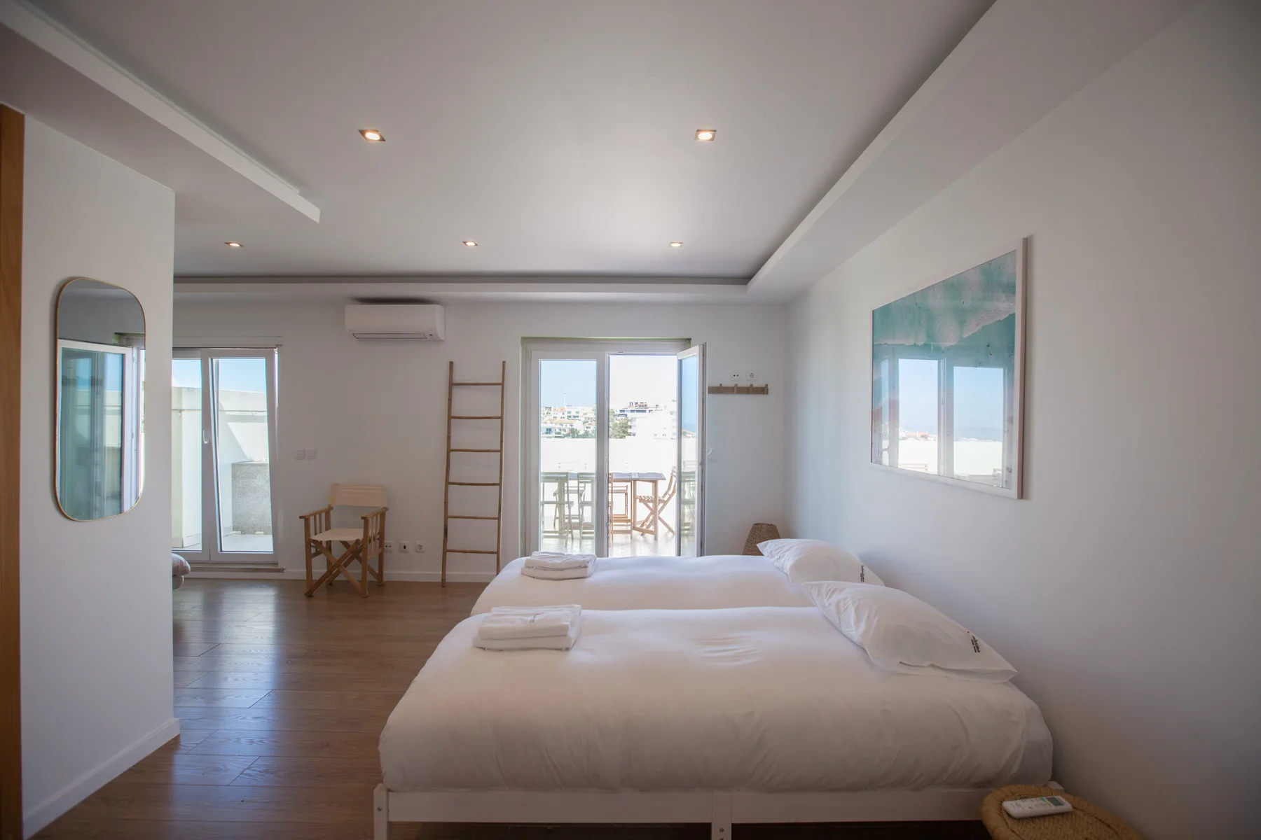 A bright bedroom with beds and glass doors opening onto a balcony.