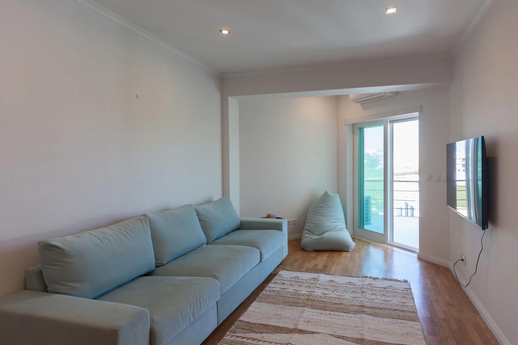 A living room with seating, a rug, and glass doors opening onto a balcony.