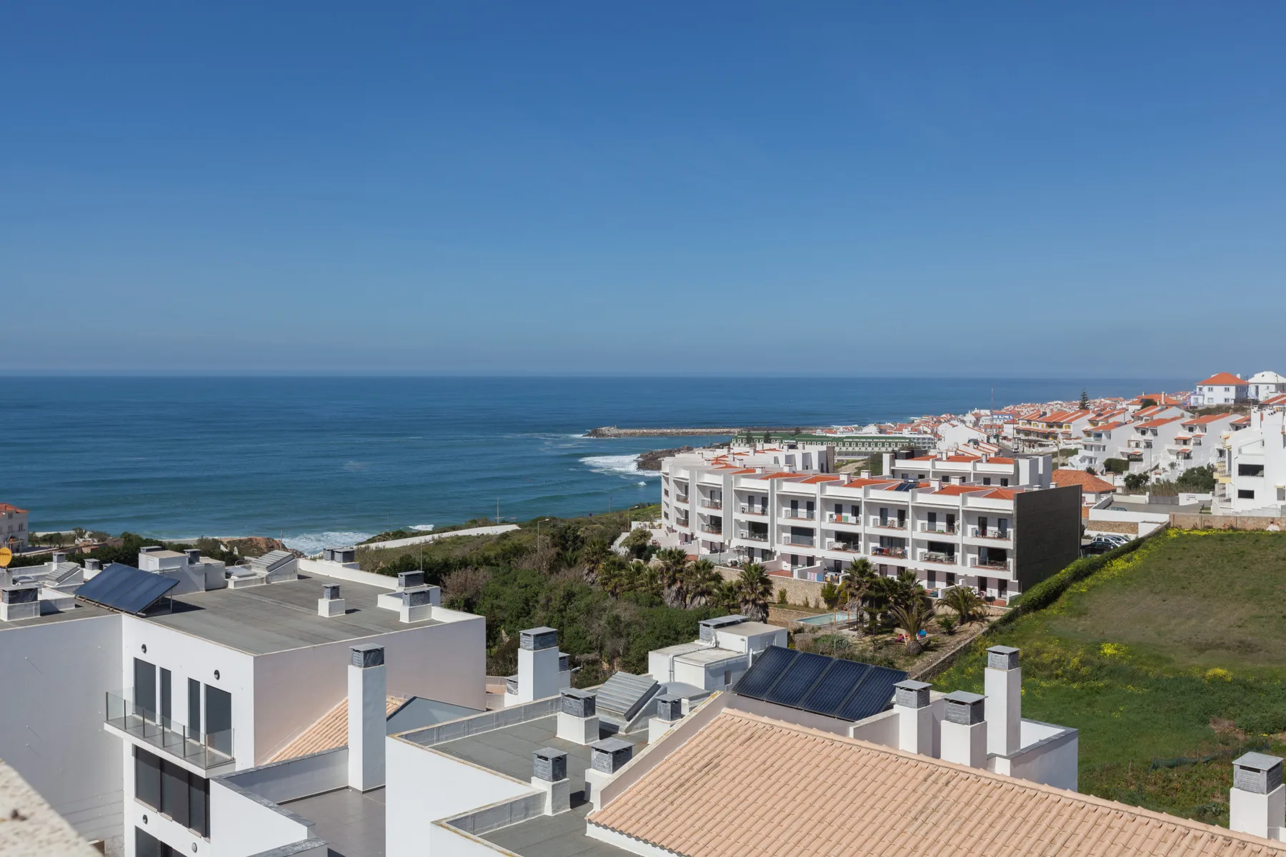 Coastal town with white buildings overlooking the ocean under a clear sky.