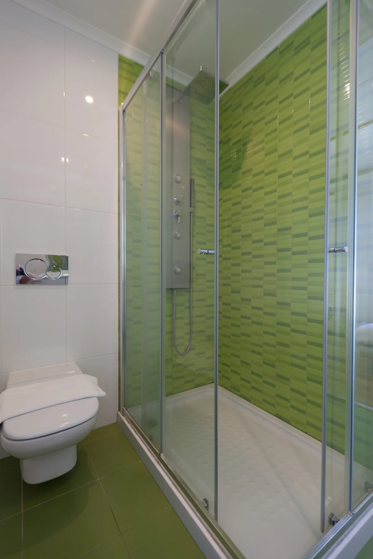 A bathroom with a glass-enclosed shower and wall-mounted toilet.