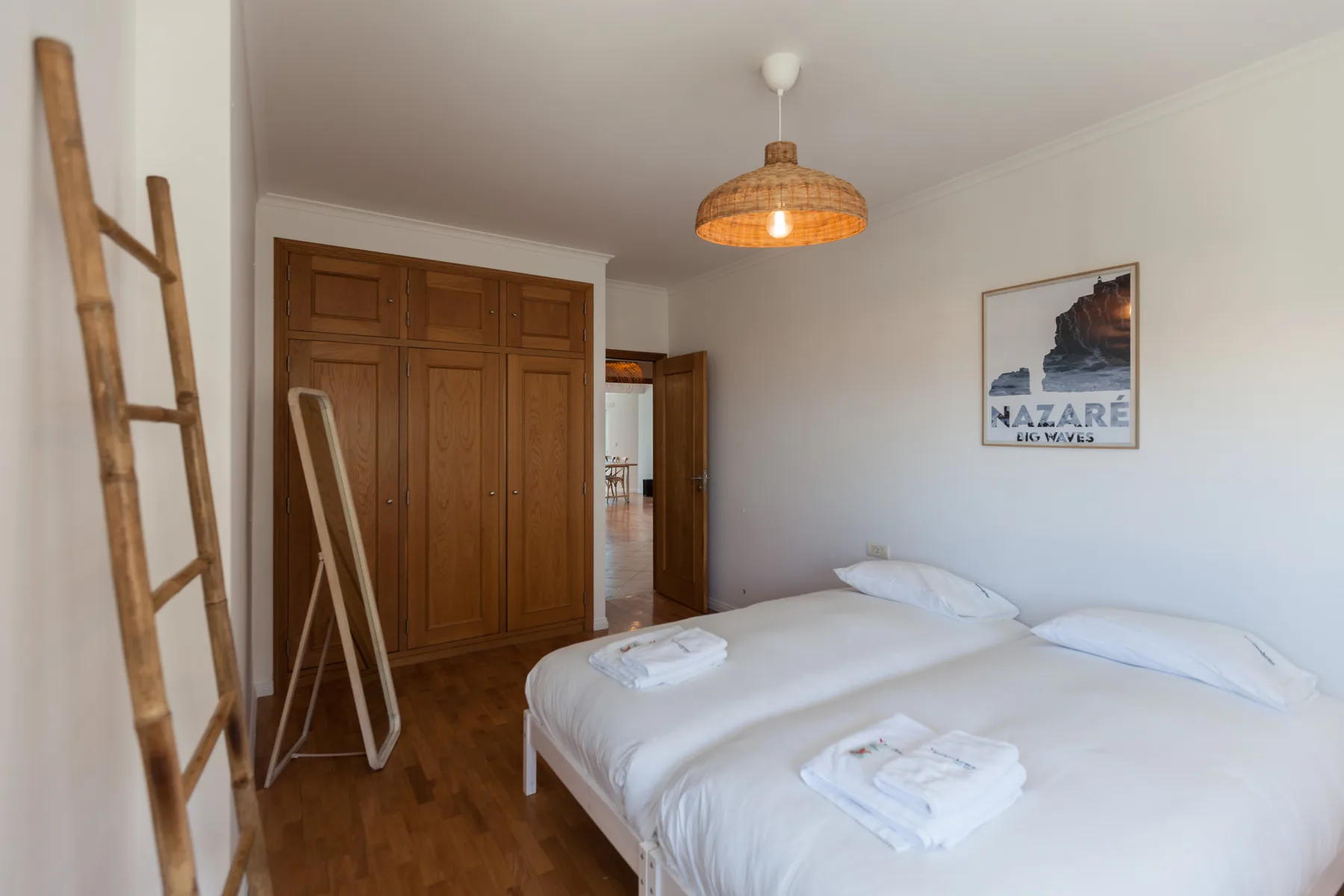 A bedroom with a large bed, wooden wardrobe, and hanging pendant light.