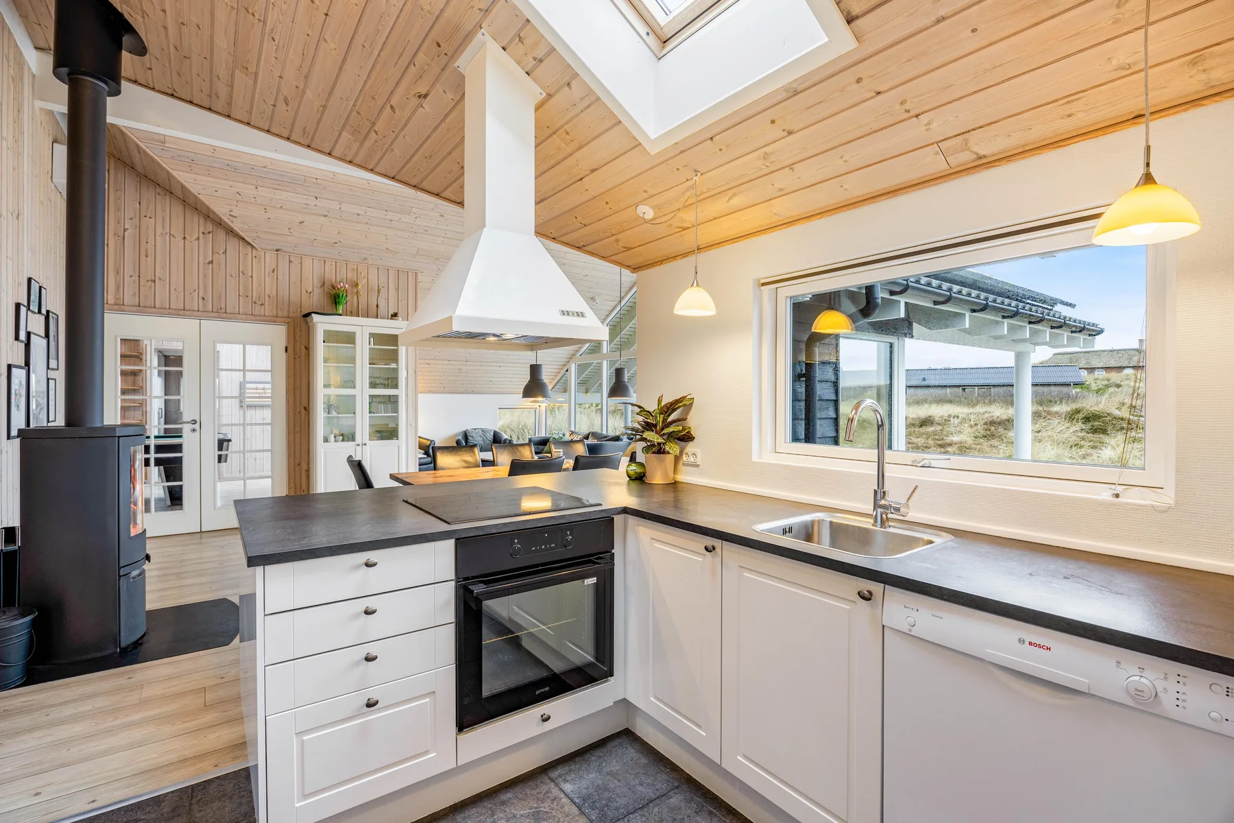 Una cocina luminosa con armarios blancos, encimeras oscuras y una ventana amplia.