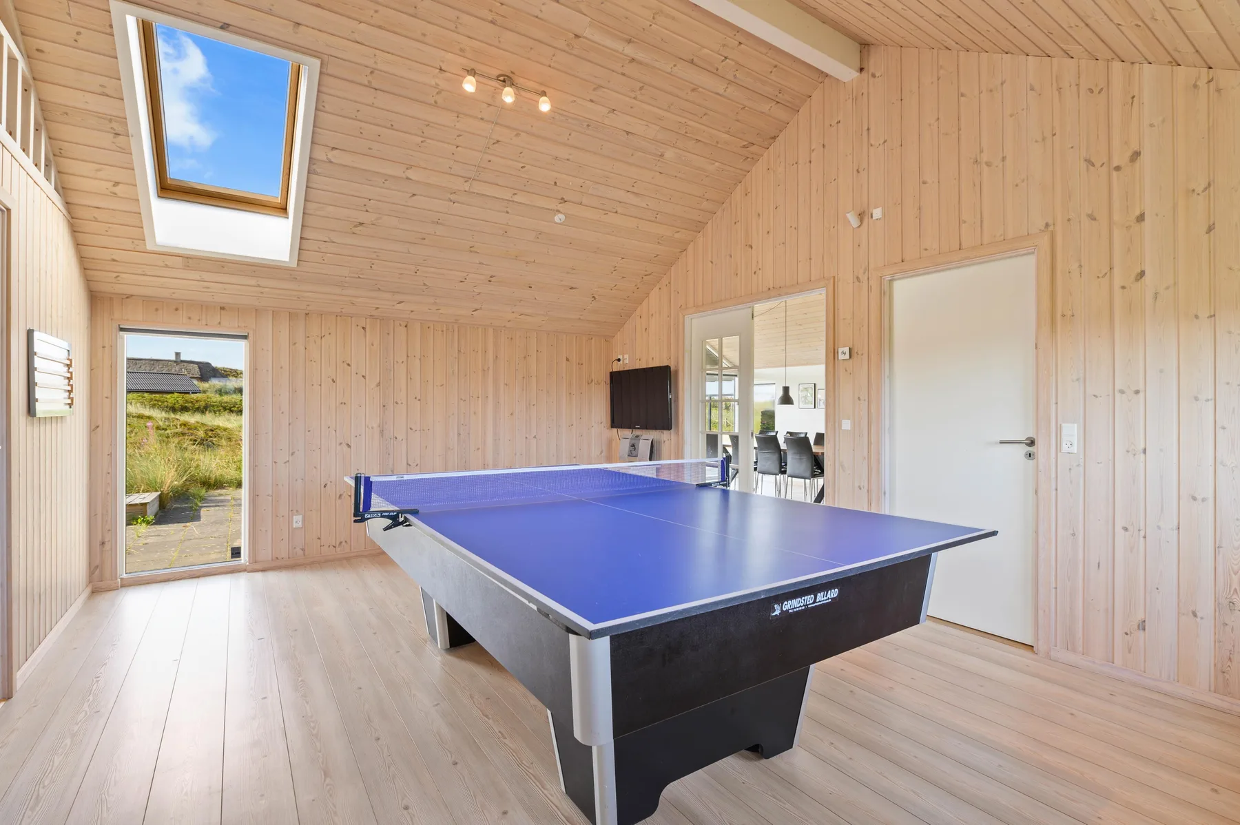 Una sala de juegos revestida de madera con una mesa de tenis de mesa azul.