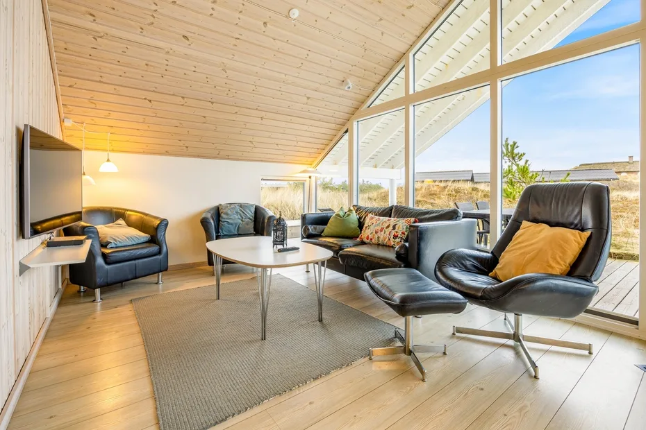 Una sala luminosa con asientos alrededor de una mesa de centro junto a grandes ventanas.