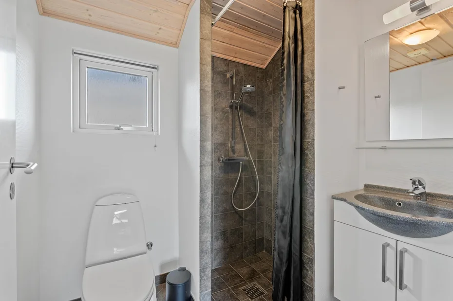 Un baño con inodoro, ducha y lavabo con mueble.
