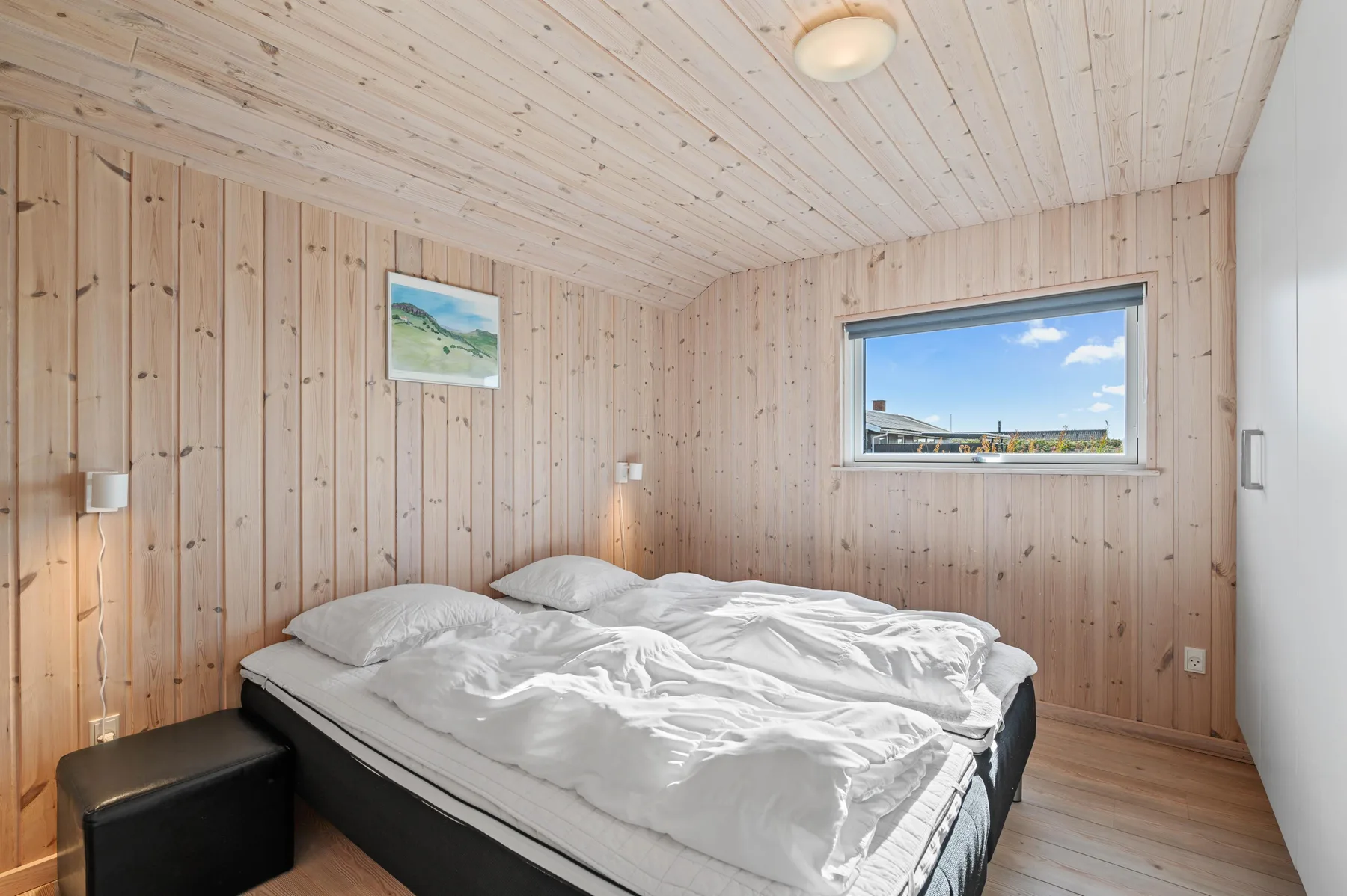 Un dormitorio con una cama bajo una ventana con vistas al paisaje.