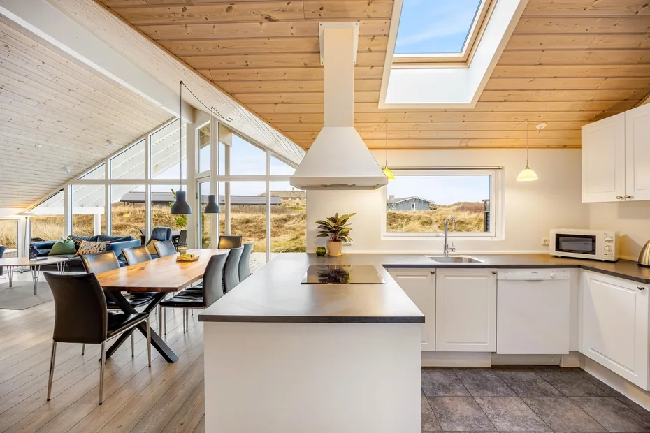 Cocina y comedor de concepto abierto con una isla central y grandes ventanas.