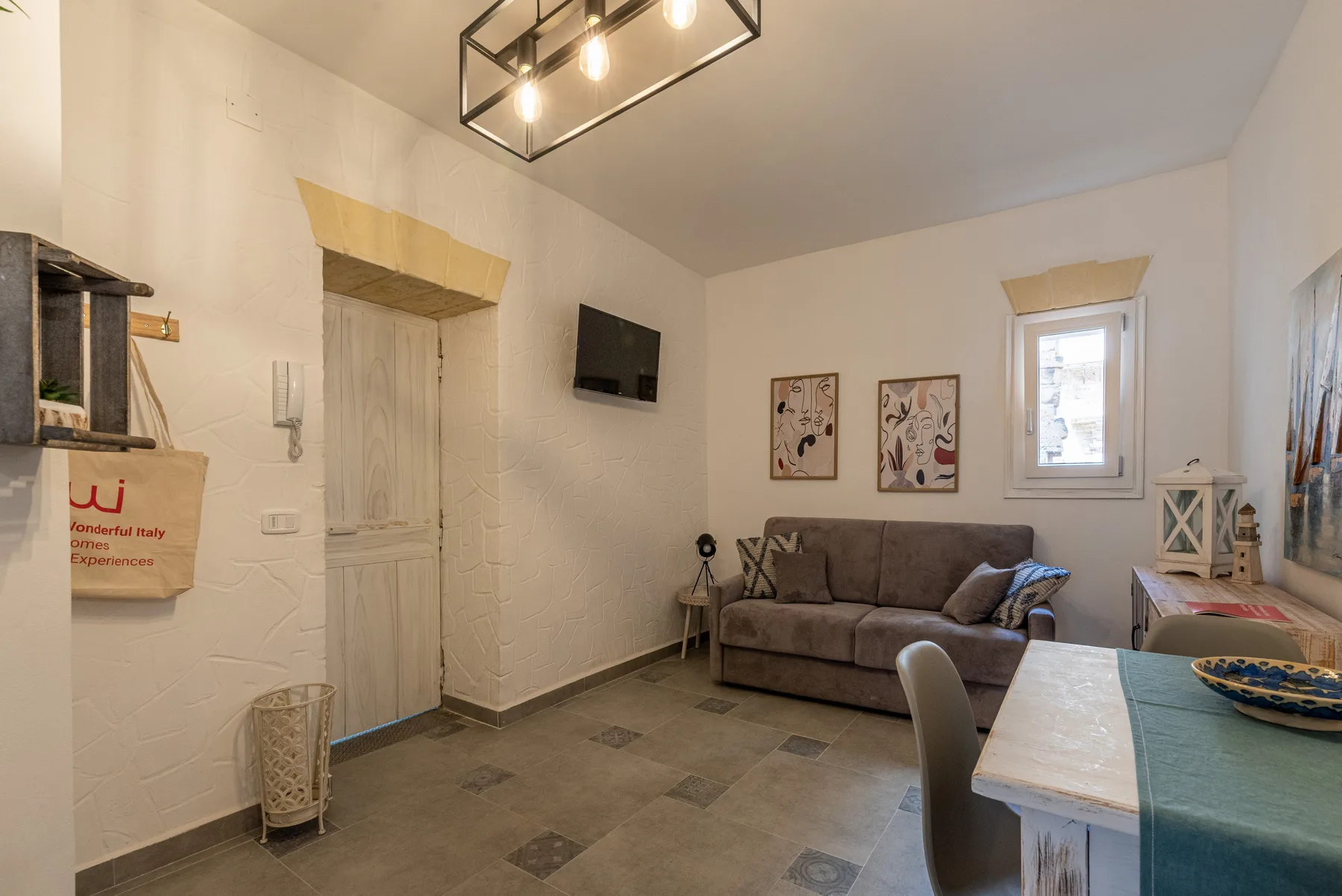 A living room with a sofa, wall-mounted television, and dining table.
