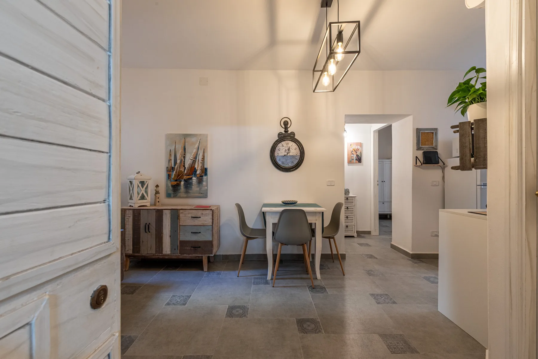A bright dining area with a table and chairs beside a painted sideboard.