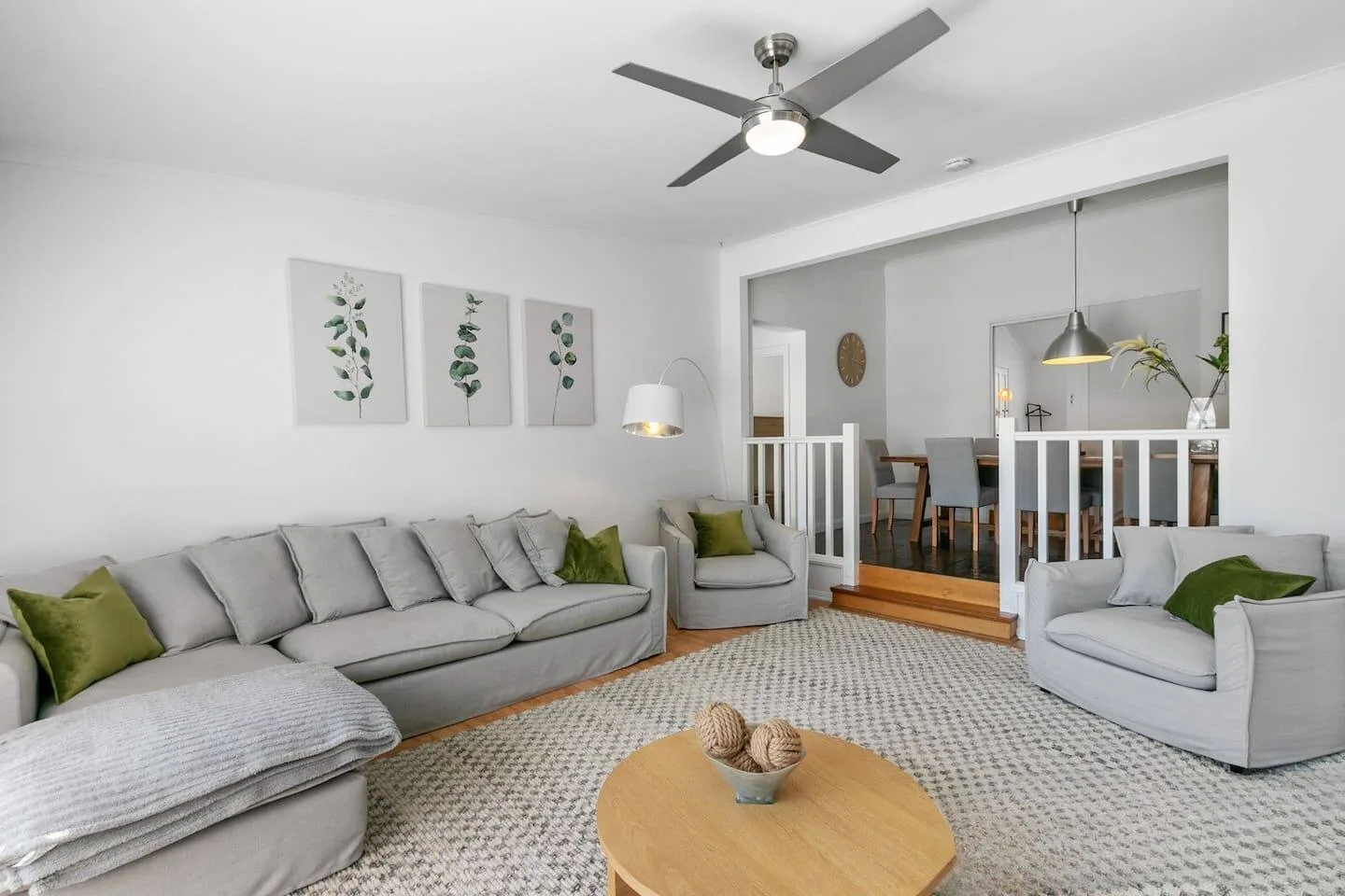 A bright living room has gray seating, a patterned rug, and an open dining area.