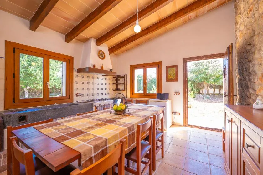 Una cocina y comedor con una mesa larga bajo vigas de madera expuestas.