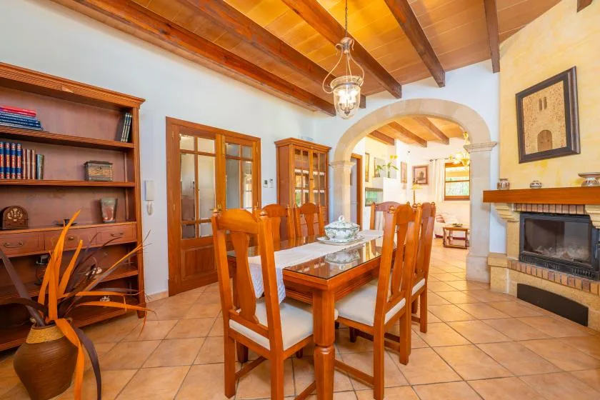 Un comedor con una mesa y sillas de madera bajo vigas de techo expuestas.