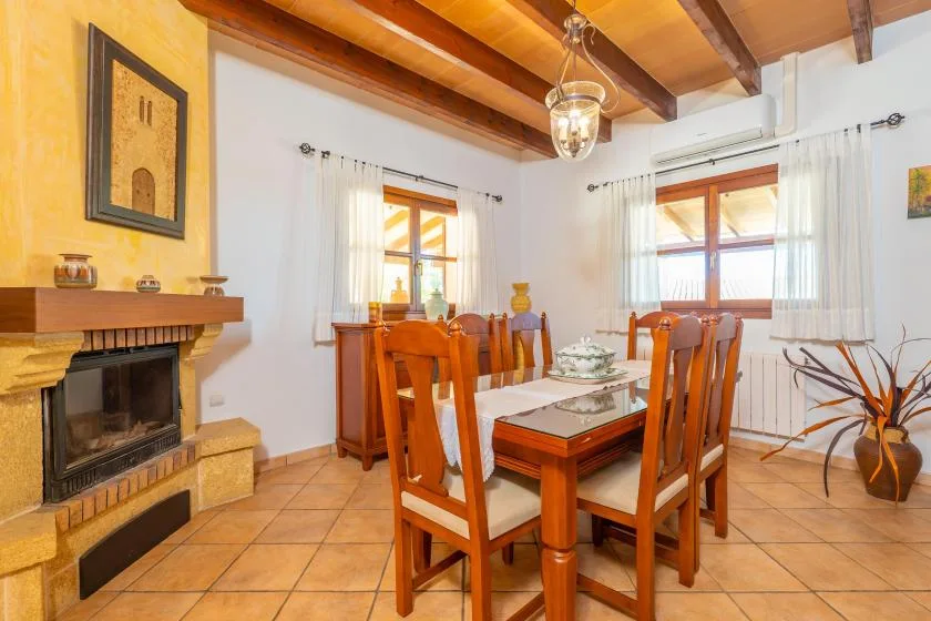 Comedor con una mesa y sillas de madera bajo vigas expuestas en el techo.