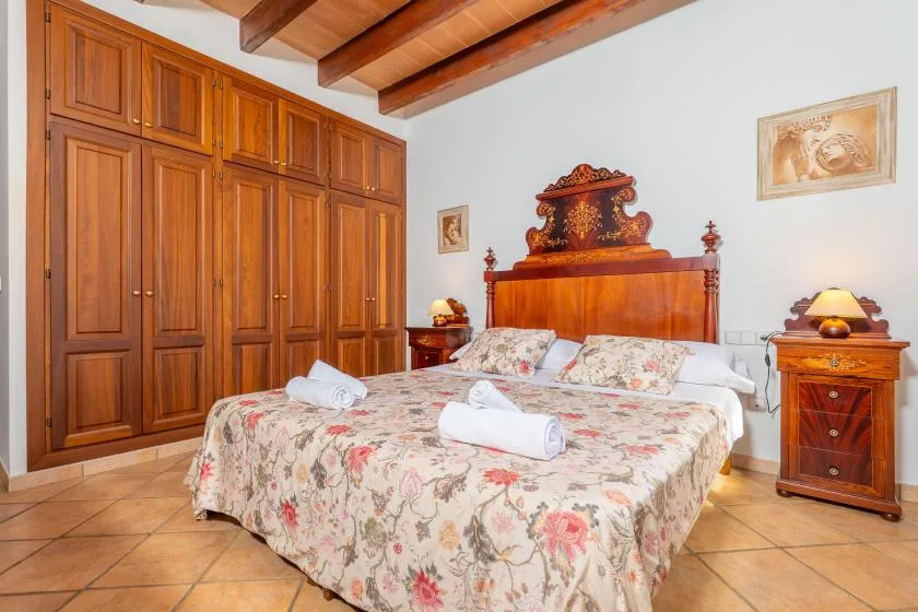 Un dormitorio con cama de madera, ropa de cama floral y armarios empotrados.