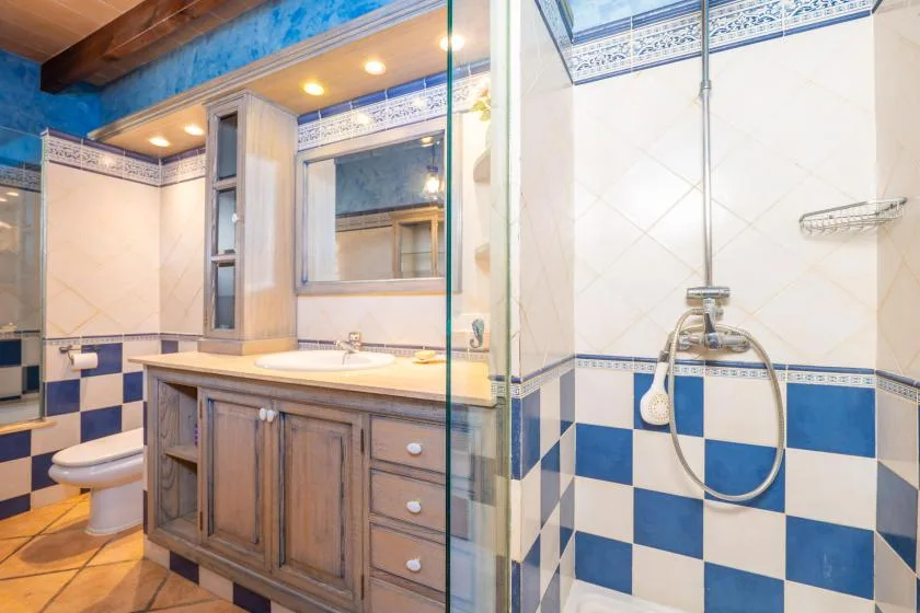 Un baño con azulejos, un mueble de madera, lavabo y ducha.