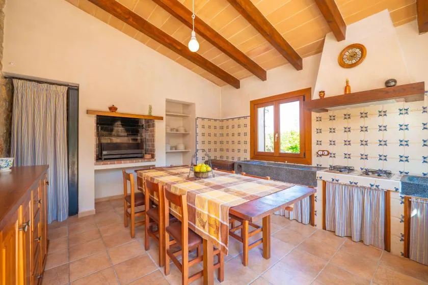Una cocina amplia con una gran mesa de madera bajo vigas expuestas en el techo.