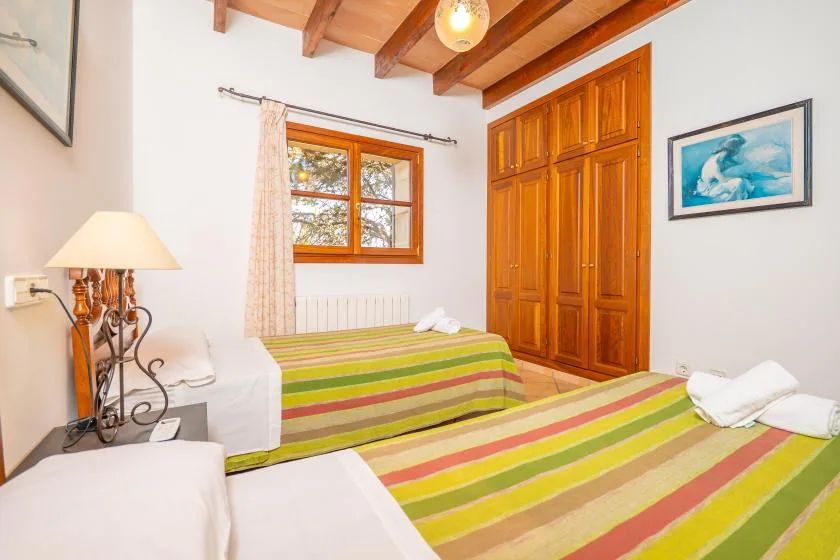 Un dormitorio con ropa de cama a rayas, armarios de madera y una ventana.