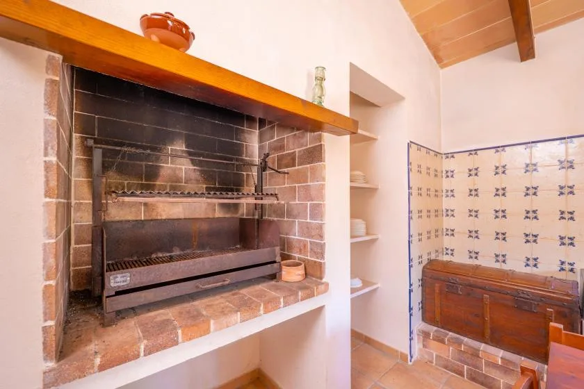 Una chimenea de ladrillo con una rejilla metálica está junto a una pared de azulejos.