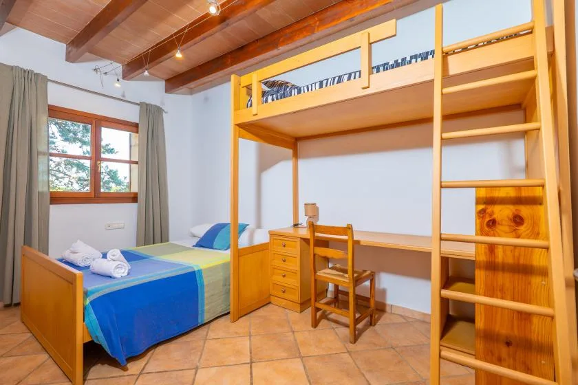 Un dormitorio con una cama junto a una cama alta de madera y un escritorio.