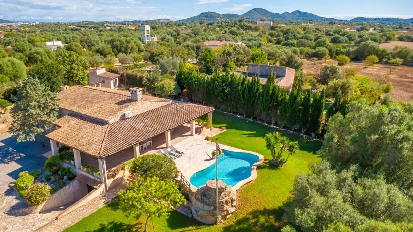 Vista aérea de una casa y una piscina rodeadas de vegetación.