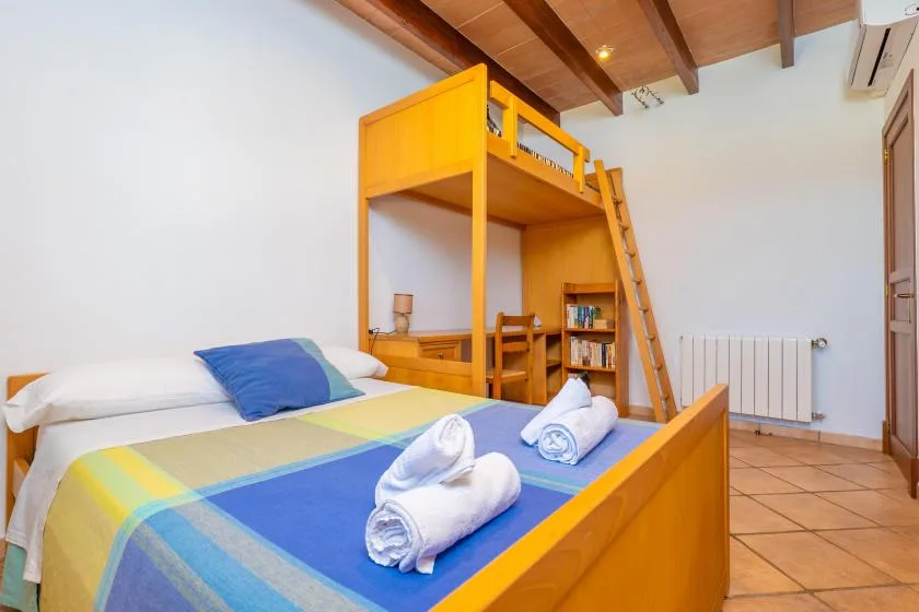 Un dormitorio con una cama alta de madera, ropa de cama colorida y toallas dobladas.