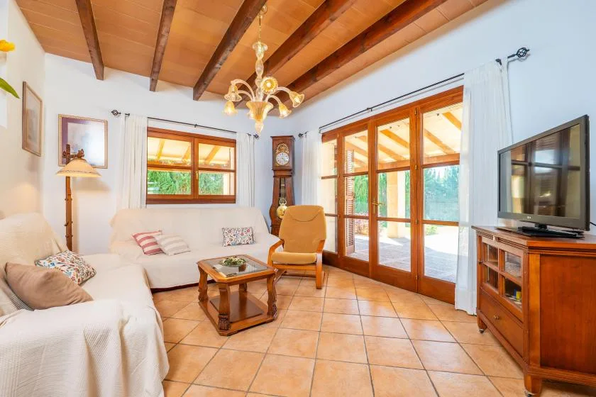 Una luminosa sala de estar con asientos, una mesa de centro y puertas acristaladas que dan a un patio.