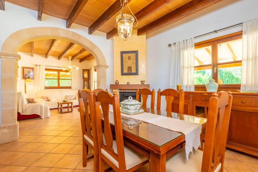 Un comedor con asientos de madera y una mesa bajo vigas de techo vistas.