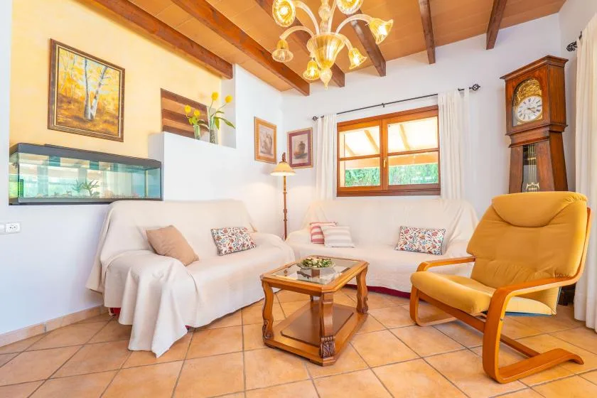 Una sala de estar con asientos blancos, una mesa de centro de madera y un sillón naranja.