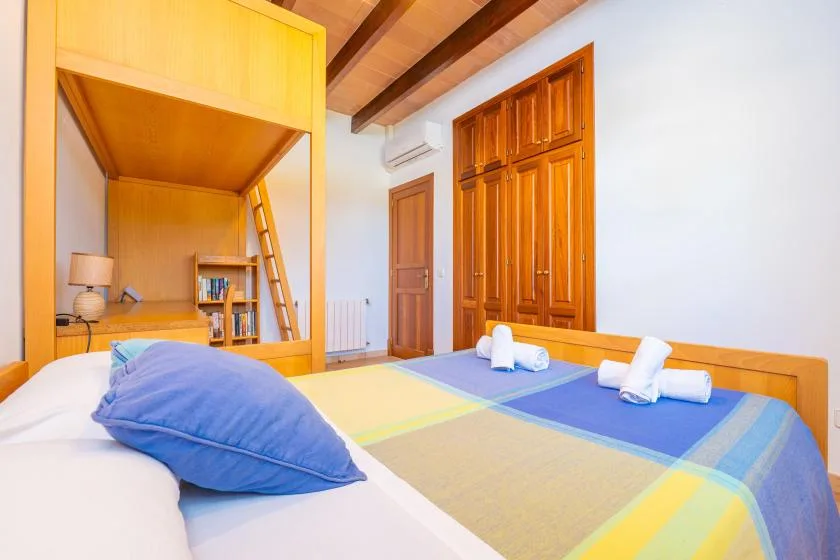 Un dormitorio con ropa de cama colorida, muebles de madera y vigas vistas en el techo.