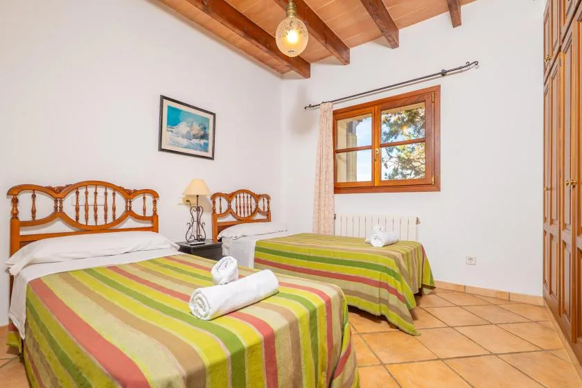 Un dormitorio con dos camas vestidas con ropa de rayas bajo un techo con vigas de madera.
