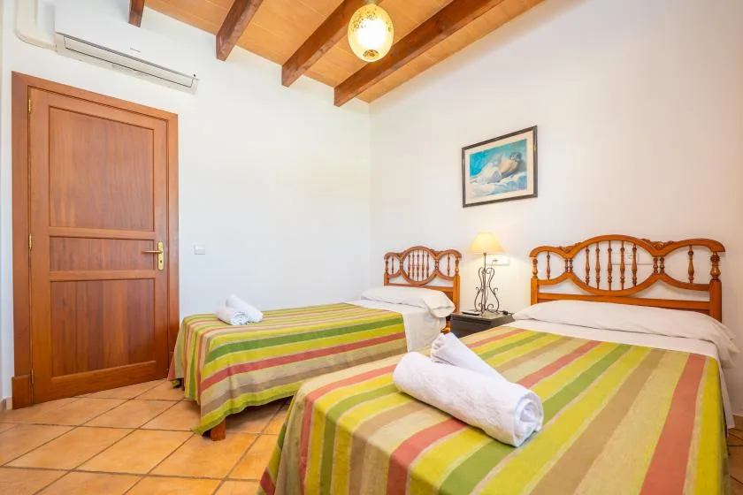 Un dormitorio con dos camas, ropa de cama a rayas y vigas de madera a la vista.