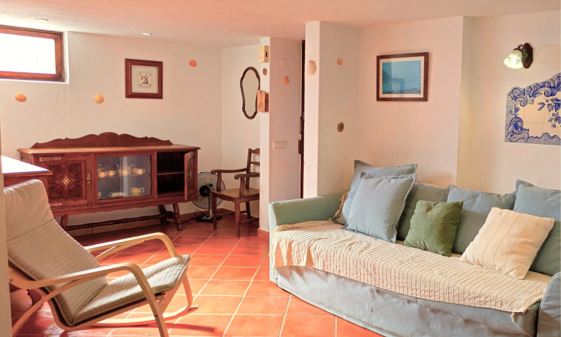 Sala de estar con asientos, cuadros enmarcados y suelo de baldosas.