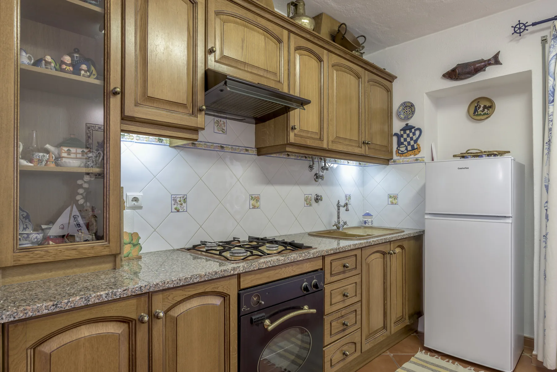 Una cocina con armarios de madera, una placa de cocina y un refrigerador.