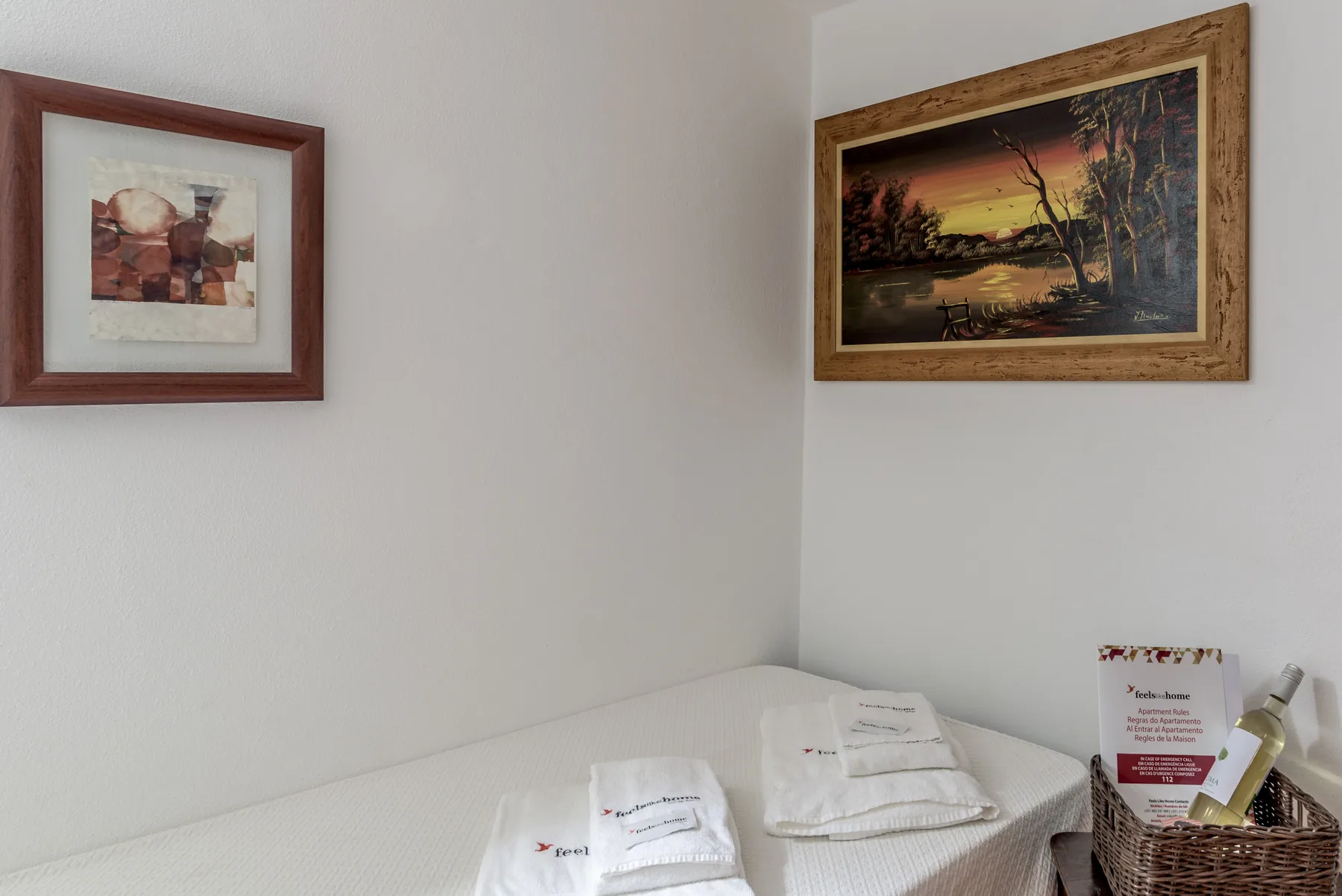 Dormitorio con una cama bien arreglada bajo cuadros enmarcados.